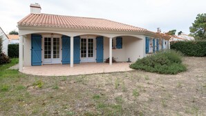 Une maison de plain-pied avec un toit en tuiles, un porche couvert doté de volets bleus et un petit jardin.