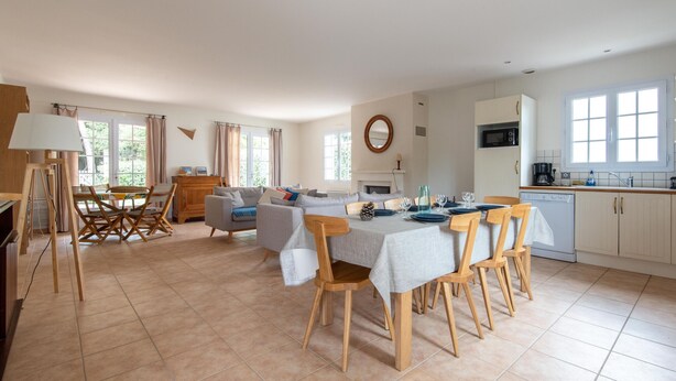 Un vaste espace de vie comprenant une table à manger pour quatre personnes, un canapé et une cheminée.