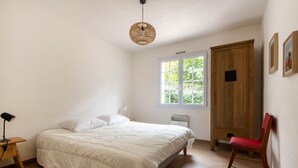 Une chambre à coucher avec un lit, une armoire en bois, une fenêtre et une chaise.