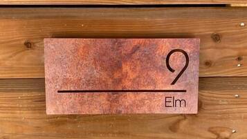 A wooden wall with a rectangular plaque displaying the number 9 and the name 'Elm'.