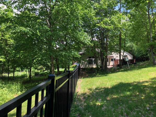 A fenced yard with a house and a bird feeder.