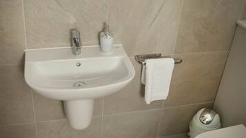 Ein Badezimmer mit weißem Waschbecken, Handtuchhalter und Toilette.