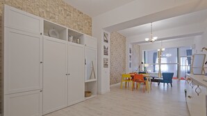 Una habitación amplia con un armario grande, un comedor con mesa y sillas, y vistas a través de un ventanal.