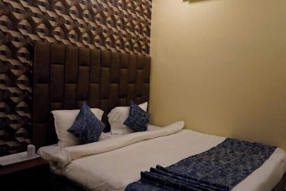 A bed with a tufted headboard, white bedding, and blue pillows.