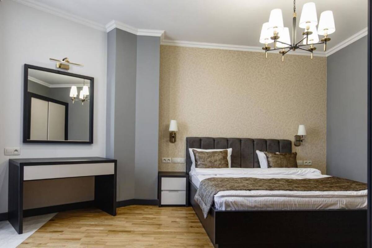 Ein Schlafzimmer mit einem Bett, Nachttischen, einem Schreibtisch und einem Spiegel.
