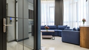 Una sala de estar moderna con un sofá azul, una mesa de centro de madera y un jarrón con flores.