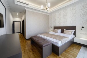 Een moderne slaapkamer met een groot bed, een bankje en een bureau.