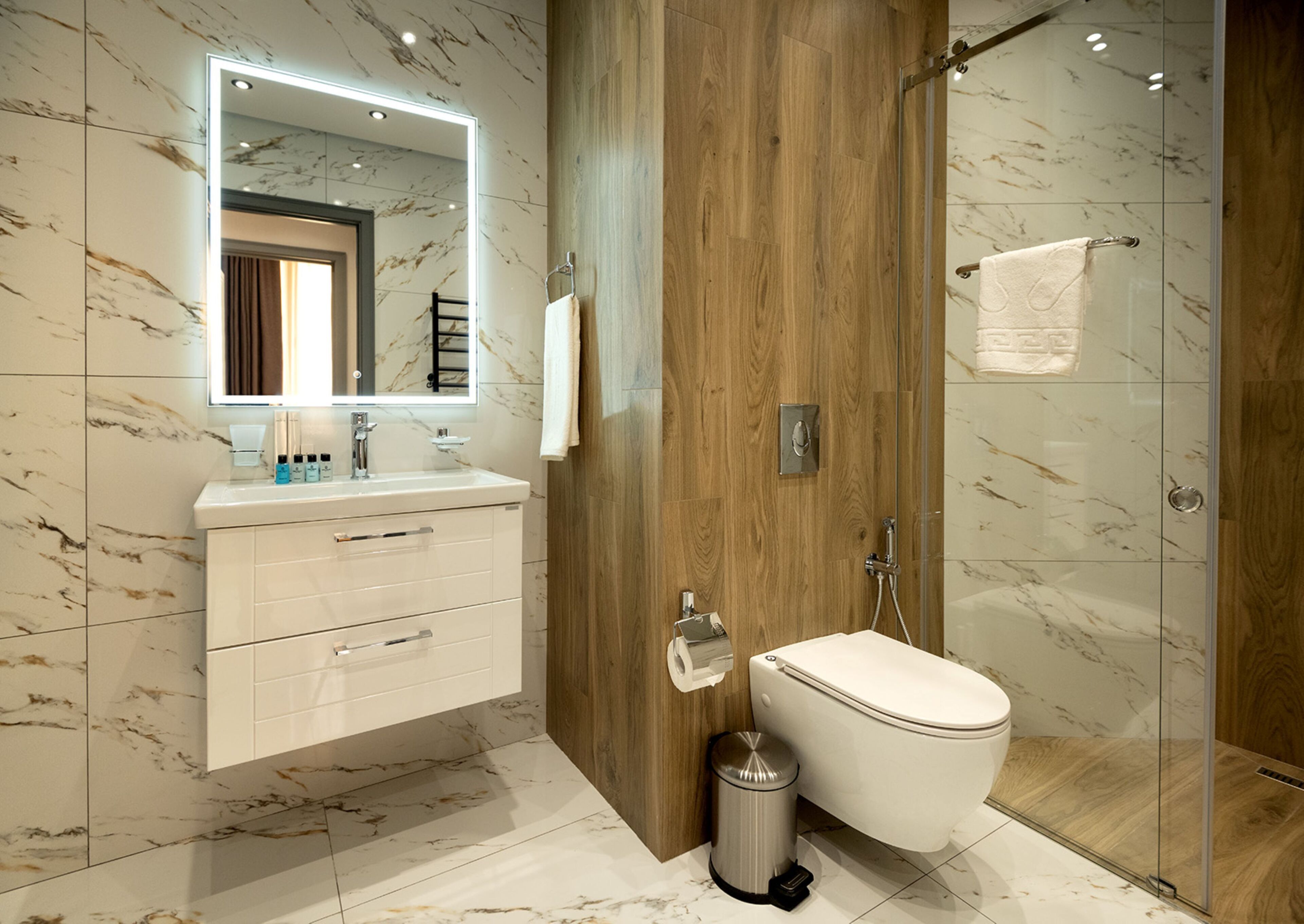 A modern bathroom with a marble backsplash, wooden paneling, a glass shower enclosure, and a white vanity with a mirror.