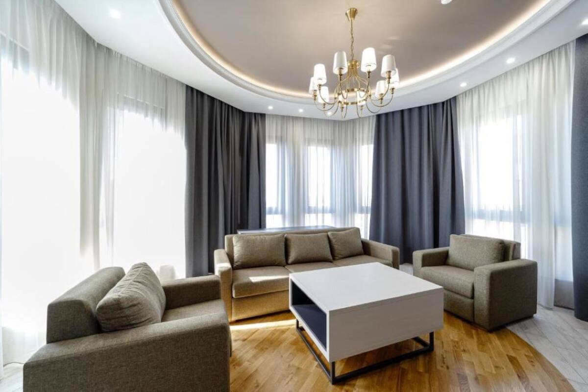 Ein modernes Wohnzimmer mit einer Sofagarnitur, einem Couchtisch und einer Deckenleuchte.