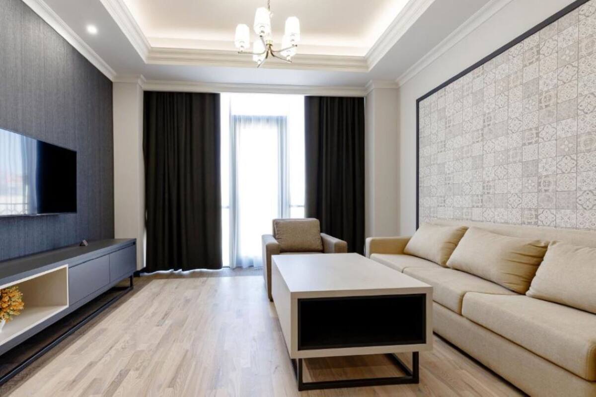 Ein modernes Wohnzimmer mit Flachbildfernseher, Sofa, Couchtisch und einer Wand mit Muster.