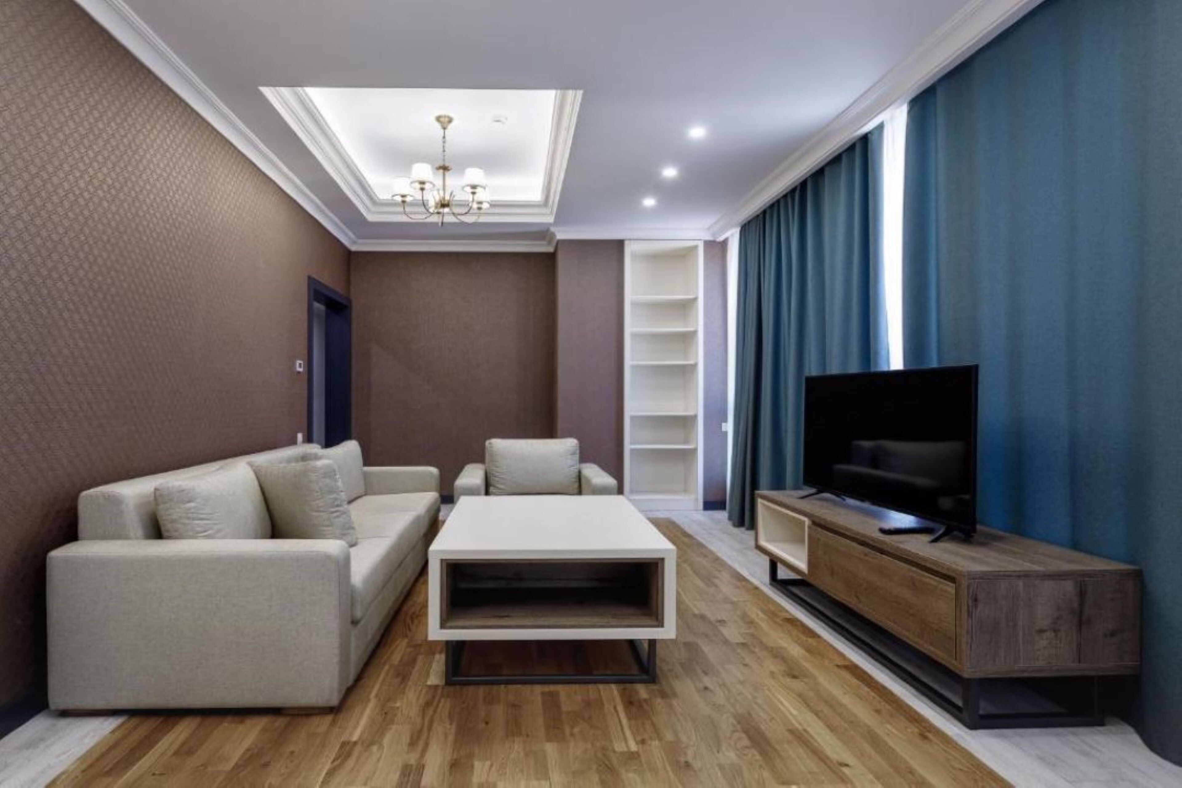 A modern living room with a sofa, coffee table, TV stand, and built-in shelves.