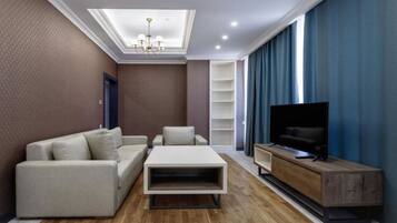 A modern living room with a sofa, coffee table, TV stand, and built-in shelves.