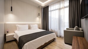 Una habitación de hotel moderna con una cama grande, un sofá, una mesita de madera y un escritorio.