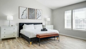 A bedroom with a bed, nightstands, a bench, and artwork on the wall. - Lewisville Estate - Spacious 5BR w/ Game Room (Lewisville)