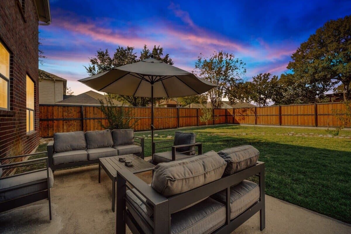 An outdoor patio with a sofa set, a table, and an umbrella.