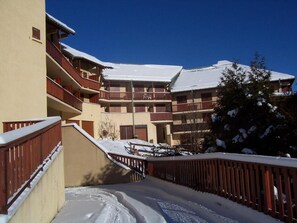 Ein mehrstöckiges Gebäude mit Balkonen und einem mit Schnee bedeckten Dach.