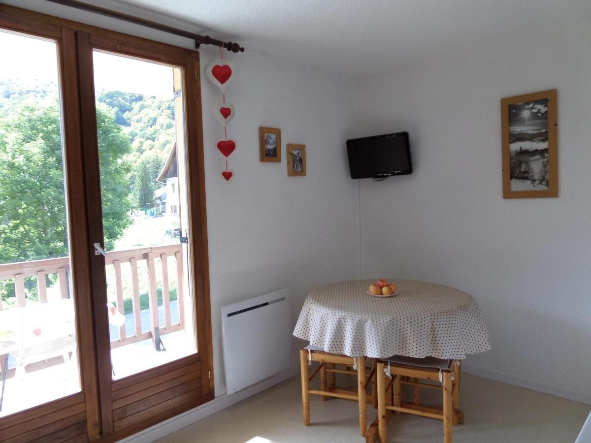 A room with a wooden-framed balcony, a small table with a polka dot tablecloth, and a wall-mounted television.
