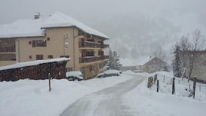 A snow-covered building with multiple balconies, a visible entrance, and a snow-covered road leading to it. - 1st floor, parking, 26m², Valloire (Valloire)