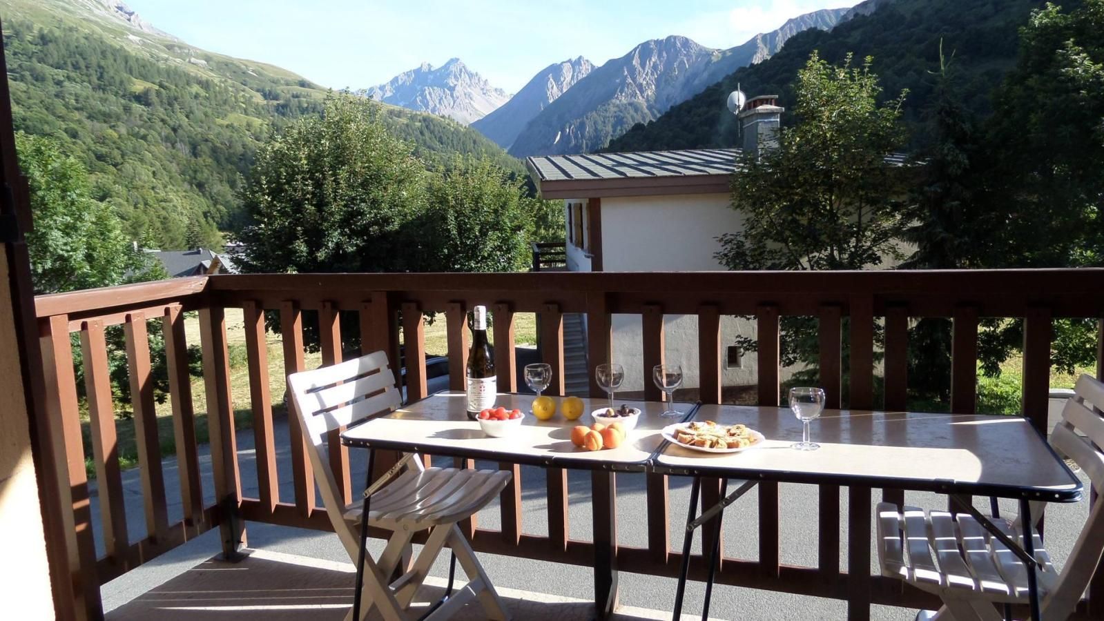 Un balcón con una mesa lista para dos personas, con vistas a un paisaje montañoso.