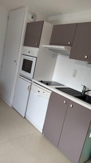 Eine kompakte Küche mit Einbauofen, Mikrowelle und Geschirrspüler, die ein modernes Design mit neutralen Farbnuancen aufweist.