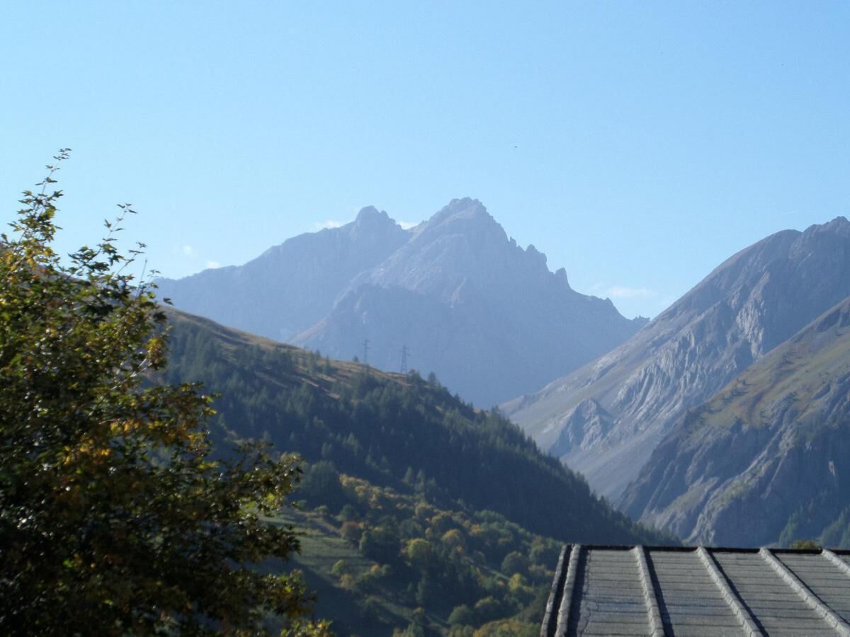A mountainous landscape with a valley and a building with a sloped roof.