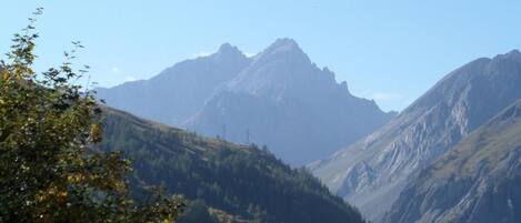 A mountainous landscape with a valley and a building with a sloped roof.