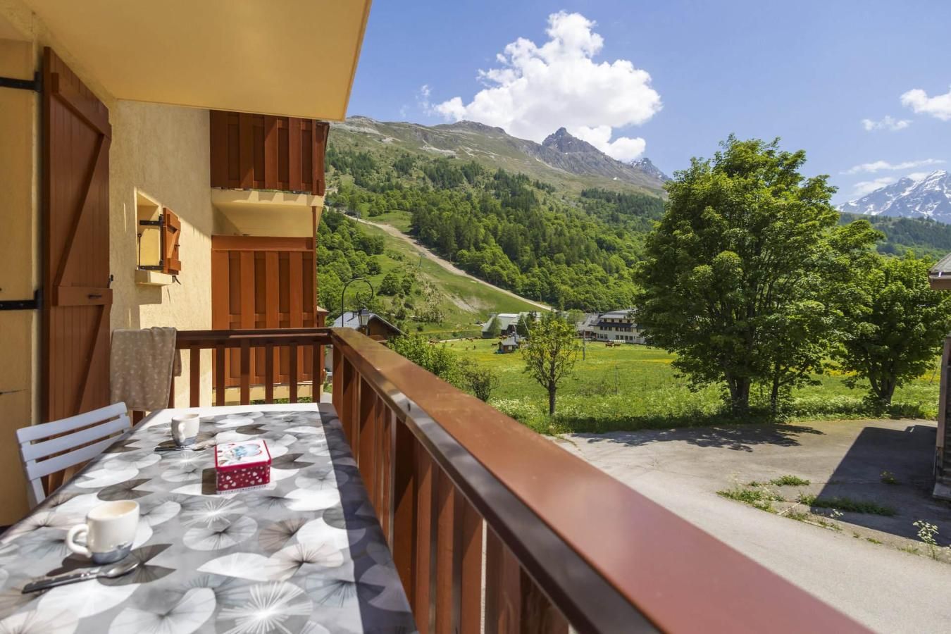 Een balkon met een eettafel voor twee personen, met uitzicht op een bergachtig landschap onder een heldere lucht.
