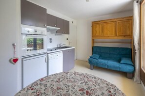 A compact kitchen with modern appliances, a sofa, and a heart-shaped decoration on the wall.