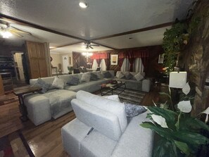 A living room with a sectional sofa, a coffee table, and a chandelier. There is a staircase leading to another level.