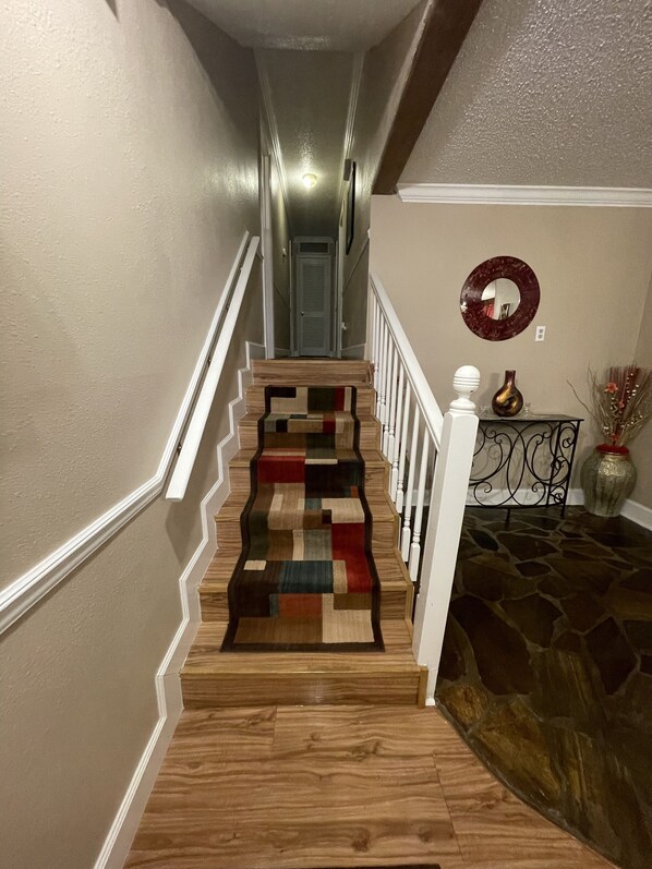 A staircase with a wooden handrail and a patterned carpet.