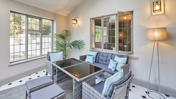 A sunlit room with a glass-top table, wicker furniture, and a floor lamp.