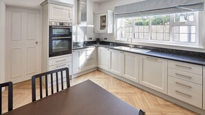 A modern kitchen with white cabinetry, a black countertop, and a window with a view.