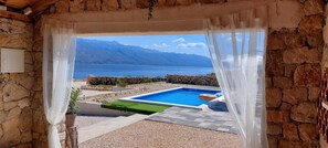 A stone-walled room with a view of a swimming pool and mountains. - Villa Mareni Zadarvillas (Razanac)
