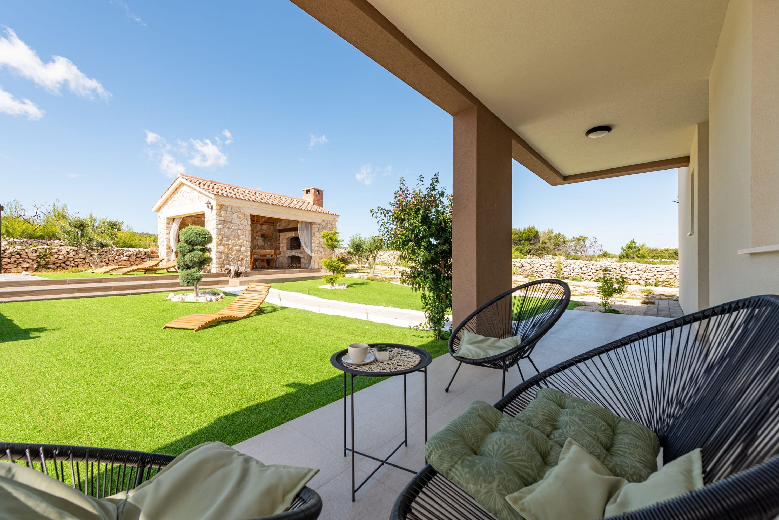 A patio with outdoor furniture, a stone building in the background, and a well-maintained lawn.