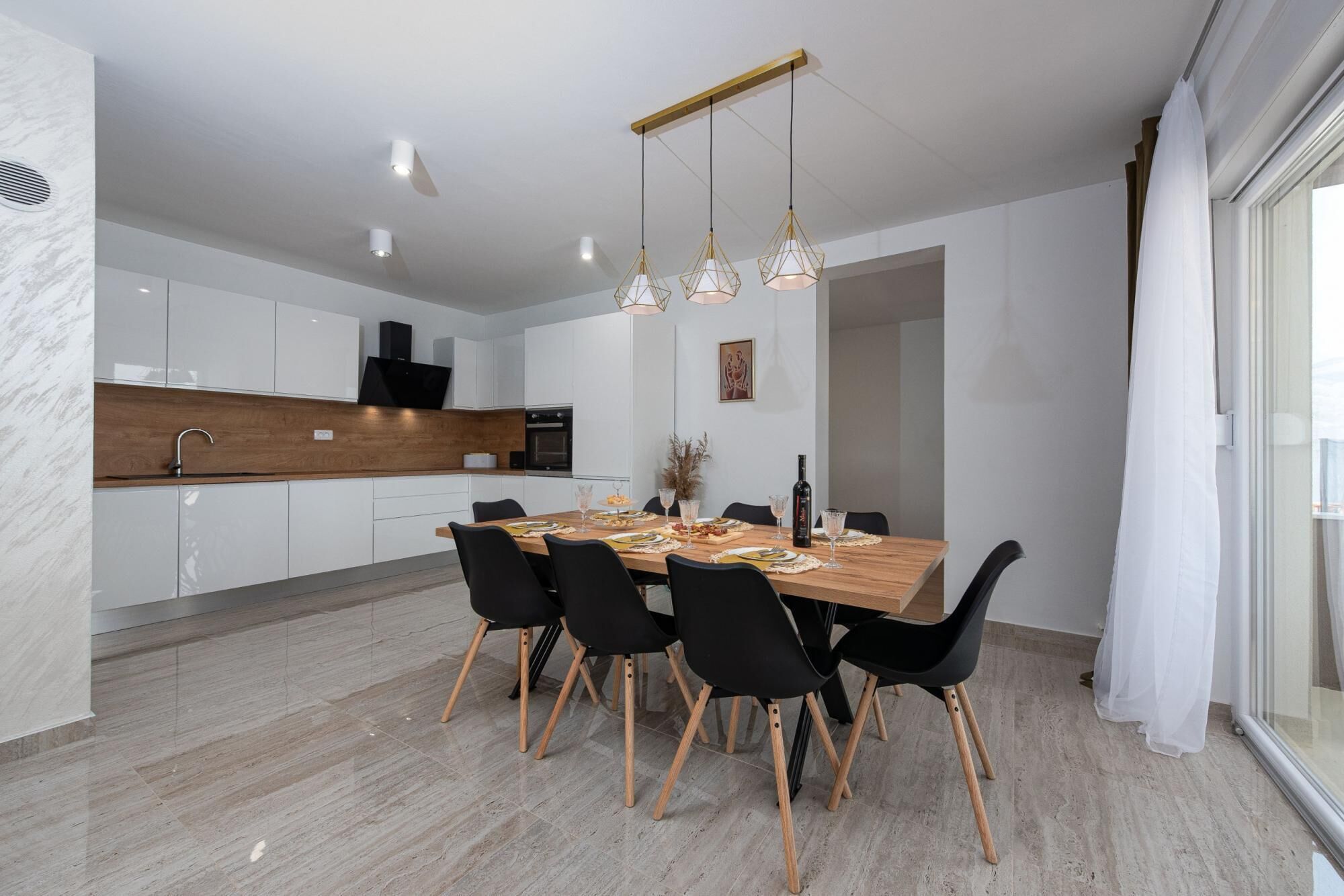 A modern kitchen with white cabinets, a wooden countertop, and a built-in oven.