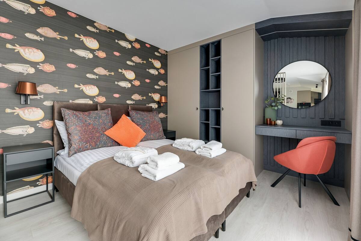 Une chambre bien rangée, avec un lit, une table de chevet, un bureau avec une chaise, un miroir et une armoire.