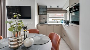 Une cuisine moderne avec un coin repas, un téléviseur à écran plat et une vue sur l’extérieur.