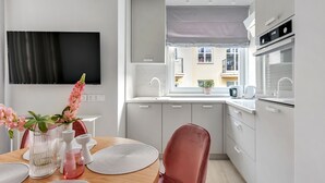 Une cuisine moderne avec un coin repas, une grande fenêtre et un téléviseur à écran plat fixé au mur.