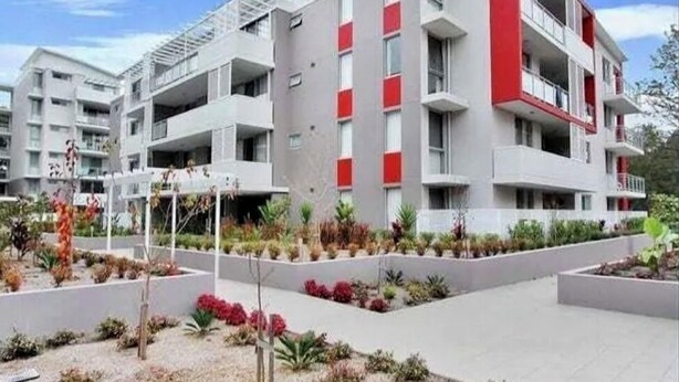 Un edificio moderno a più piani con balconi, immerso in giardini curati.
