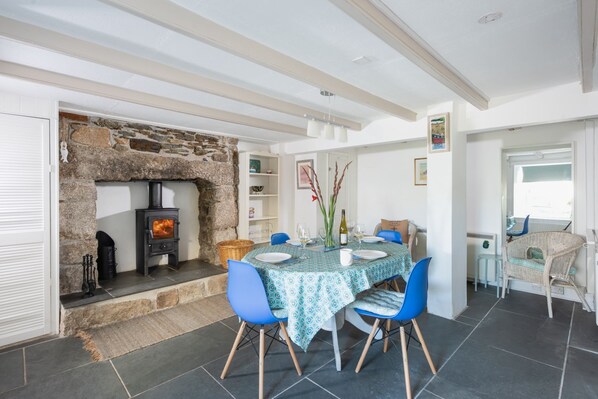 A dining area with a stone fireplace, blue chairs, and a table set for four.
