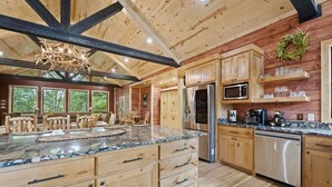 A spacious kitchen with wooden cabinets, granite countertops, and modern appliances. - Grand Overlook Resort | Luxury Pool Retreat (Broken Bow)