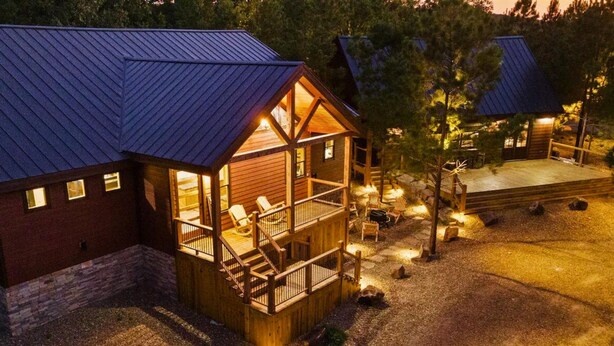 A cabin with a wooden deck and a covered porch, surrounded by trees. - Grand Overlook Resort | Luxury Pool Retreat (Broken Bow)