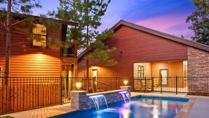 A modern house with a swimming pool, wooden exterior, and a waterfall feature. - Grand Overlook Resort | Luxury Pool Retreat (Broken Bow)