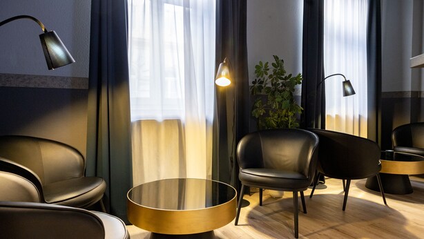 Un área de descanso moderna con sillones de cuero, una mesa redonda e iluminación ambiental.