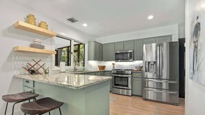 A modern kitchen with a central island, stainless steel appliances, and a view to the outdoors.