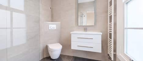 A modern bathroom with a toilet, vanity, and a mirror.