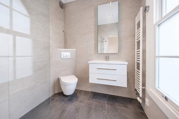 Un baño moderno con inodoro, tocador y espejo.