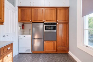 Una cocina con armarios de madera, un refrigerador de acero inoxidable, un horno empotrado y una lavadora.