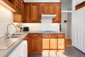 Una cocina con armarios de madera, un lavamanos de acero inoxidable y un horno empotrado.