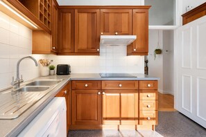 Una cocina con armarios de madera, un lavamanos de acero inoxidable y un horno empotrado.